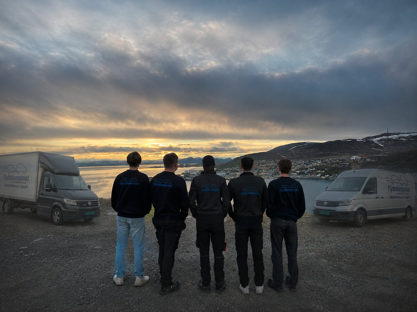 Flyttekompaniets ansatte og begge firmabilene med Hammerfest i bakgrunnen